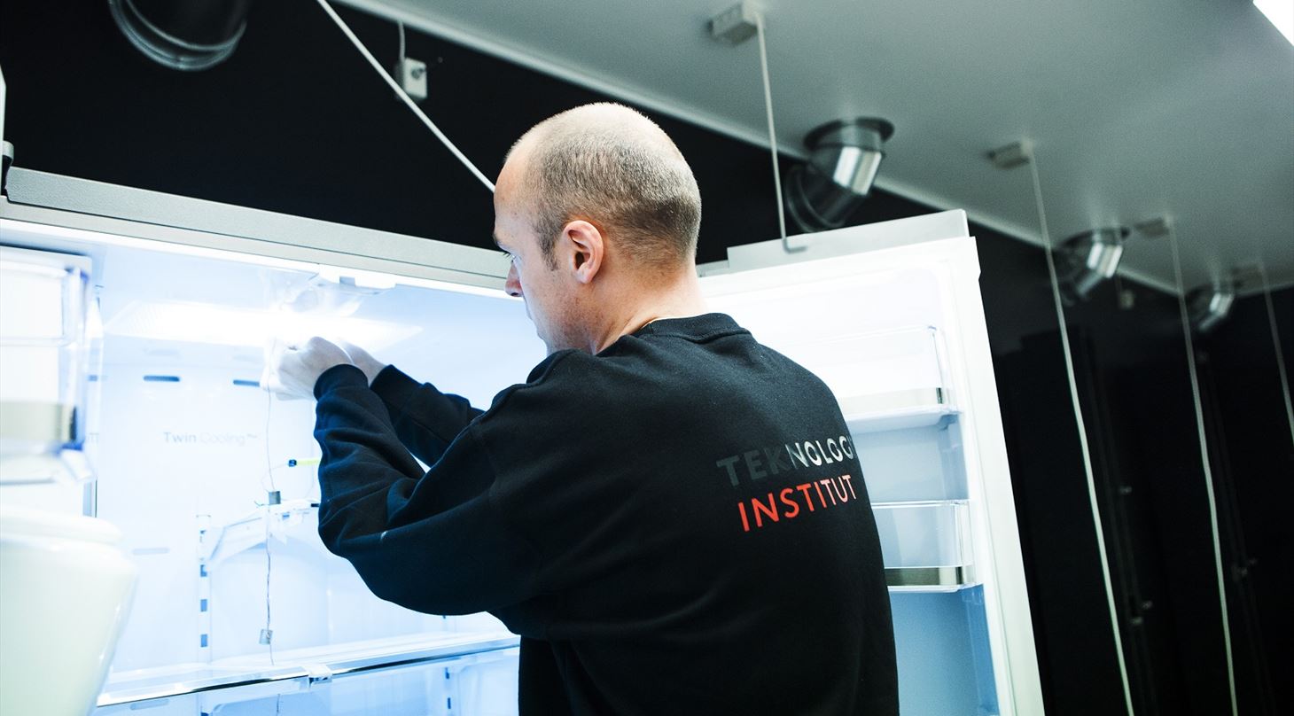 Billedet viser en person, som er ved at teste et køleskab i Energilaboratoriet på Teknologisk Institut.